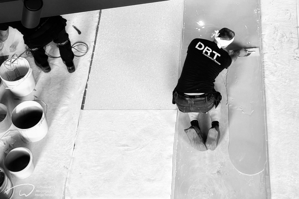 Renovation works with two construction workers creating a cast floor creating a smooth new surface.
