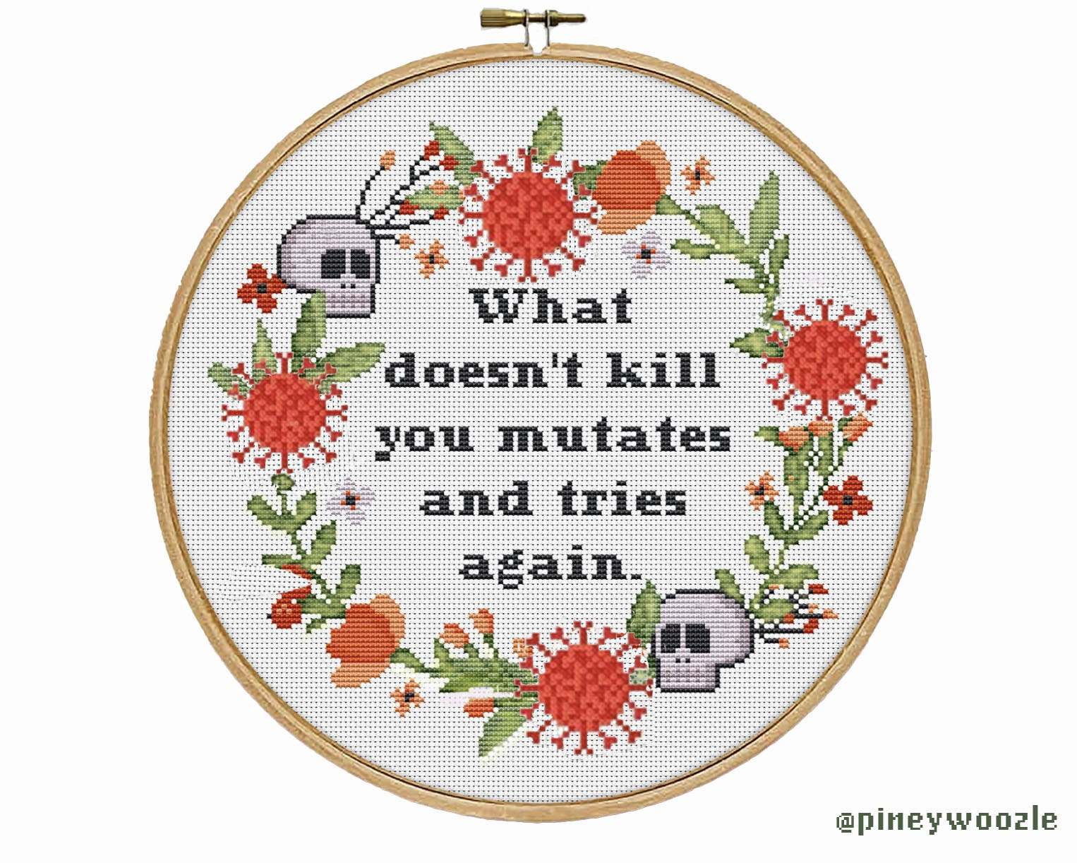 An embroidery hoop, with the words what doesn’t kill you mutates and tries again signed Piney Wilson. The image in the hoop is around the flowers is a wreath where the blossoms have been replaced by coronavirus molecules included in the reef is two small skulls.