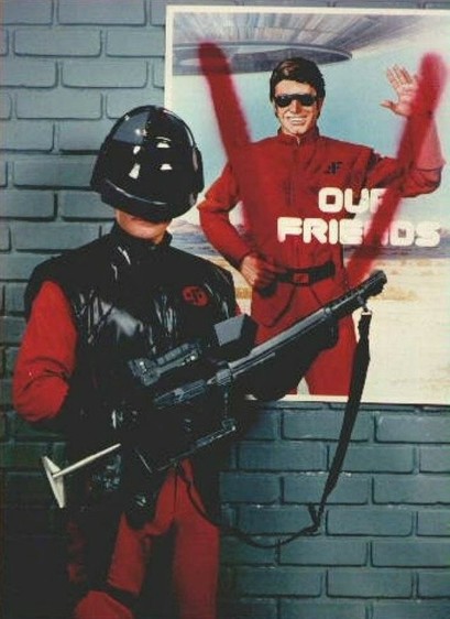 Armed alien soldier in front of a poster "Our friends" where "V" is spray-painted