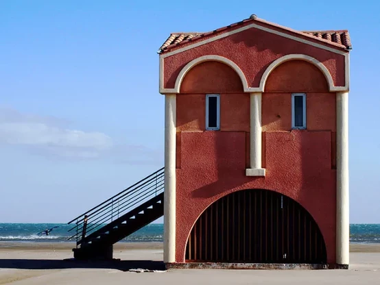 A red building on a beach, looking like a face
2 small blue windows for the eyes and an arch for the mouth