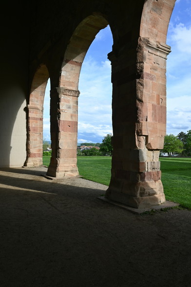 Looking along three pillars forming rounded arches now leading to green grass