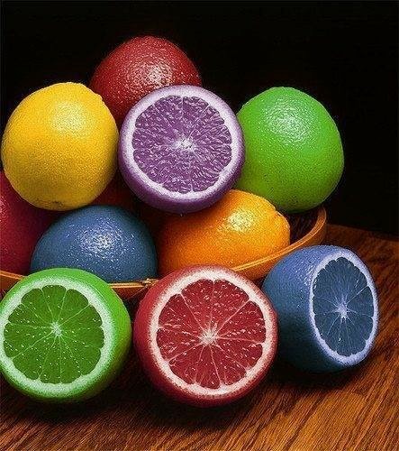 Oranges, some cut, but in multiple colors: red, blue, green, purple, yellow and orange...