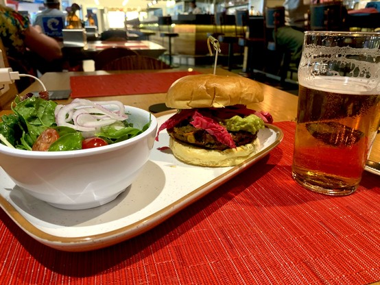 At a bar restaurant in the PHL airport, a veggie burger with pickled red cabbage and guacamole, and a side salad with an IPA.
