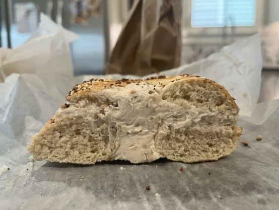 Photo of a sliced bagel absolutely packed with cream cheese.