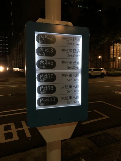 A digital display at a bus stop in Taipei. It is night. All bus lines are displayed as 