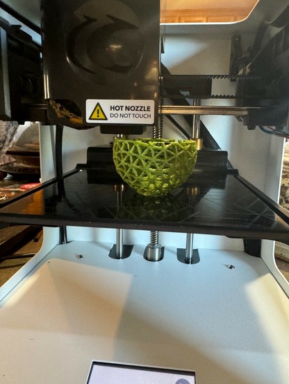 ToyBox 3-D printer making a ball out of triangular mesh in a medium green feedstock. 