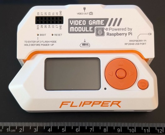 Image of a Flipper Zero device. The screen is off. The Flipper Zero Video Game Module is plugged into the top of the device.

It is sitting above a ruler sticker and appears to measure around 10.5cm in length.