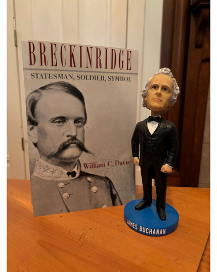 A book and a James Buchanan bobblehead on a table