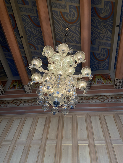 Side view of chandelier with numerous yellow globes jutting out from core. Blue spots can be seen within. 