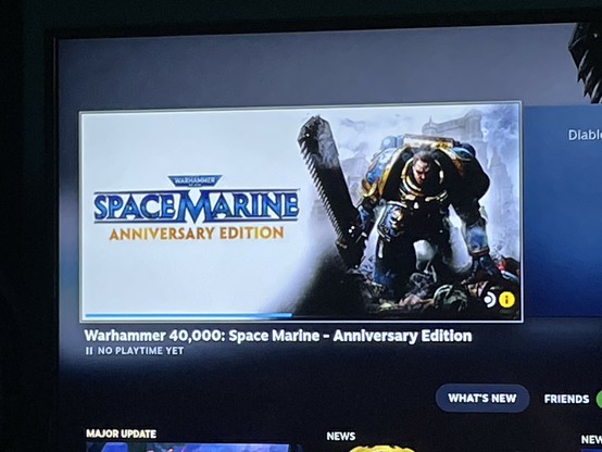 A photo of my Steamdeck showing the card for Space Marine:Anniversary Edition. The blue bar underneath shows it is about halfway through the installation process. 