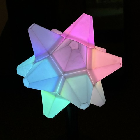 a sort of lamp type thing in the shape of an animal crossing star fragment. Technically the shape is close to a small stellated dodecahedron. It’s illuminated with a rainbow colour wheel effect. The background is very dark. There are some rough edges that need better finishing.