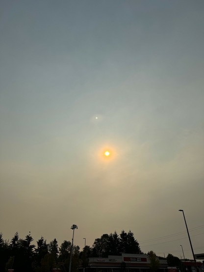 View of a hazy sky with a sun tinted to the orange due to air quality index around 90. 