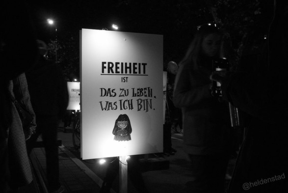 Zwart-wit foto van een bord met tekst: Freiheit ist das zu leben was ich bin. Met daaronder een getekend vrouwfiguur.