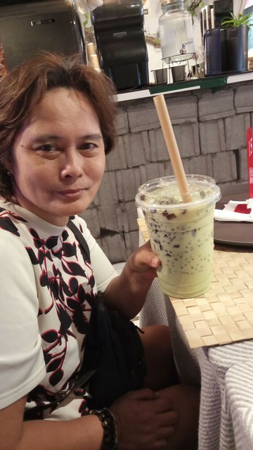My aunt holding her avocado-flavored sago't gulaman. It's in a clear plastic cup that's like almost double the size of a typical iced drink cup.