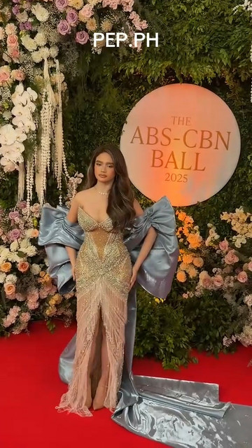 Criza Taa wearing a gold-studded dress with an oversized oversized bluish-silver satin bow train.