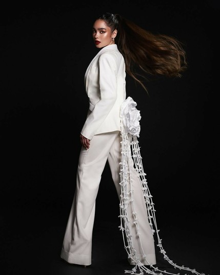 Andrea Brillantes in that same outfit, but with her back turned to the camera to reveal a wide white rose ornament on her buttocks, from which strings of white flower ornaments hang.