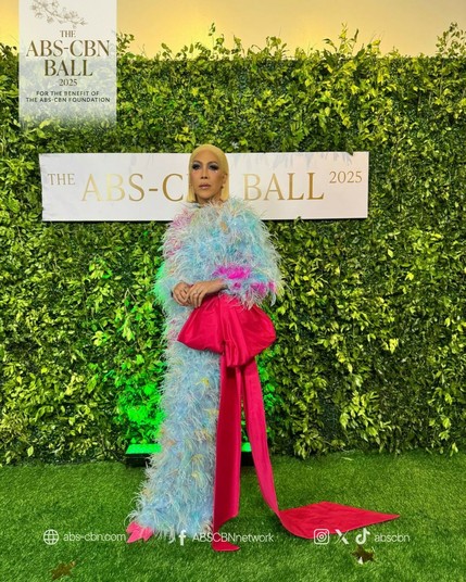 Vice Ganda in an outfit that can only be described as a more glamorous and fabulous blue and fuschia version of the Big Bird. Attached to their right hip is an oversized pink bow.