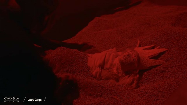 A body double wearing Lady Gaga's costume being buried underneath the sands.