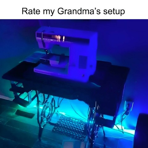 An electric sewing machine on top of a mechanical sewing machine table with teal and deep blue LED lights. Caption says "Rate my Grandma's setup."
