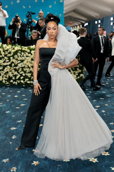 Lala Anthony wearing a black tube top that transitions into black trousers. She has a gray tulle on her left collar that extends to become half a skirt on her left side. She wears her hair on a high bun.