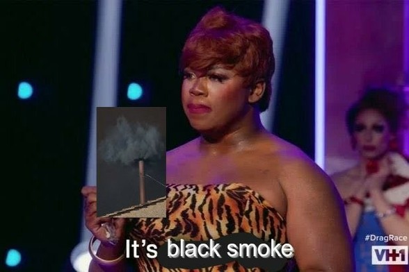 A still from Drag Race where a queen reveals a golden chocolate bar, but instead it's a picture of the black smoke from the Vatican's conclave. The queen says "It's black smoke."