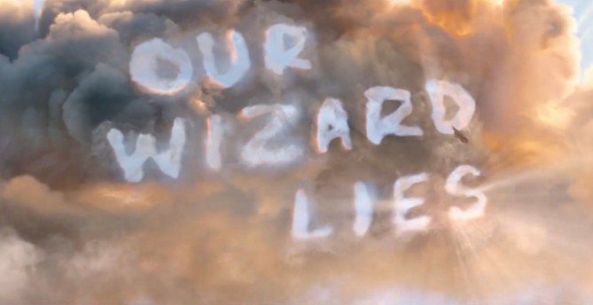 Elphaba riding her flying broomstick. She traces the words "Our wizard lies" in the dark smoke in the sky.
