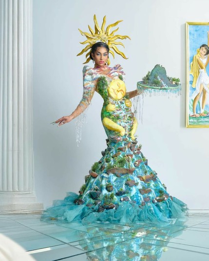 Angel from Drag Race Philippines Season 3 wearing a paper maché dress of mother nature with cliffs and waterfalls in its design. She wears rays of sunlight as her headpiece.