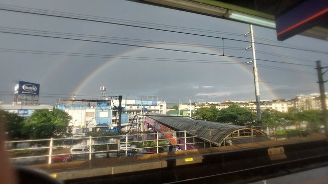 Double rainbows spanning its arcs across multiple rooftops on the city skyline.