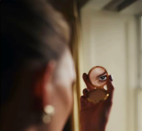 Photo from Karlie Kloss' tweet on the day of the gala. She uses a powder case's mirror to show her right eye as she looks to the camera through it.