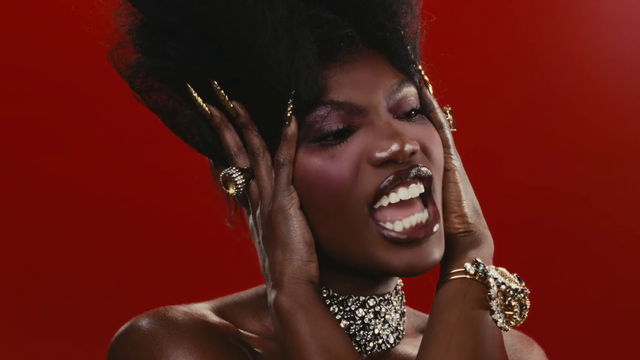 Doechii serving Egyptian queen in this closeup shot of her face as she features her long studded nails while she cups her temples with both hands.