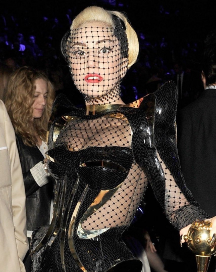Lady Gaga at the 2012 Grammys in a mesh outfit overlaid with metal corset and shoulder pads.