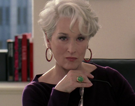 Meryl Streep as Miranda Priestly judging you with a sharp eye and her right hand under her chin.