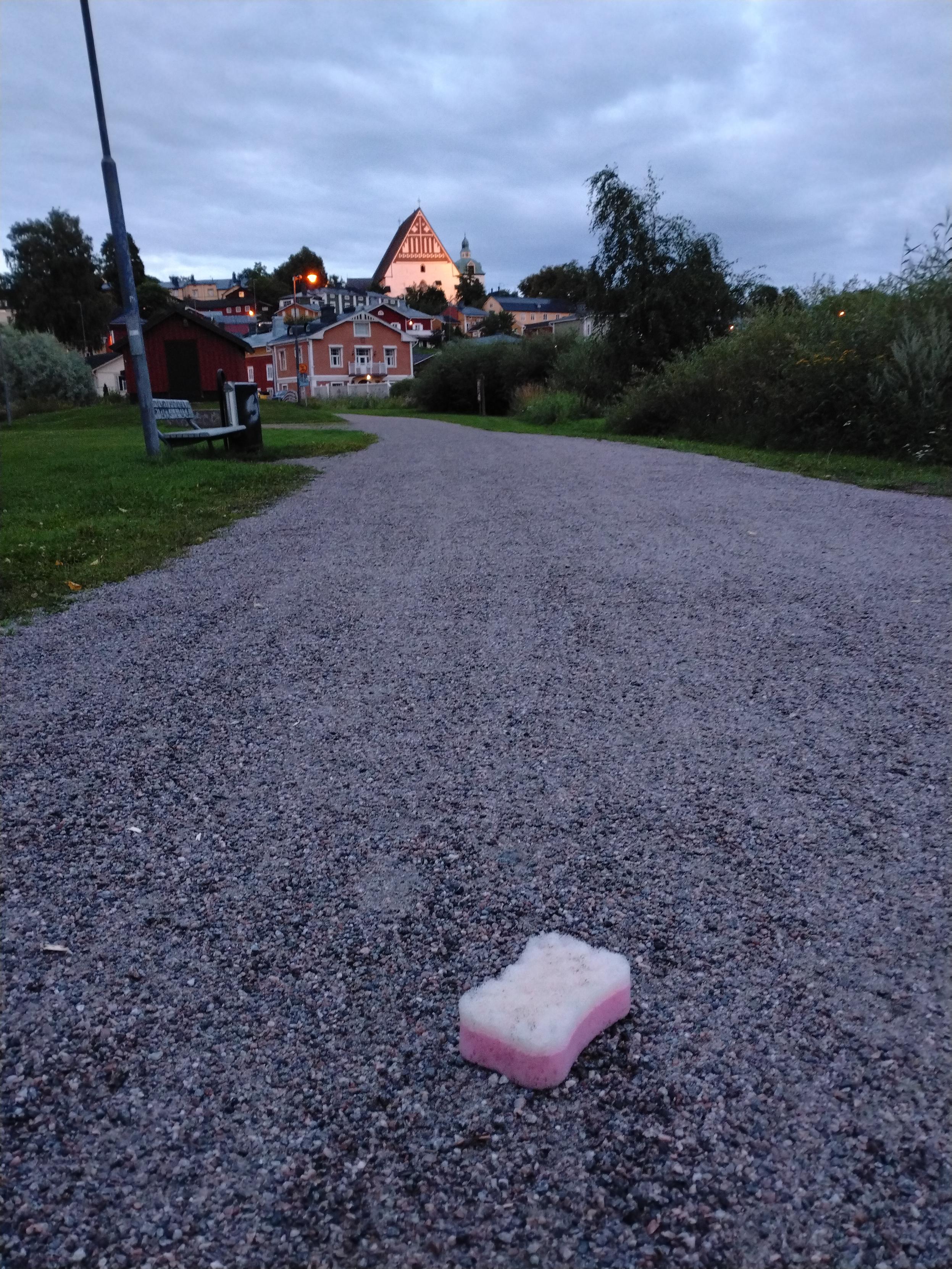 Keskellä hiekkapäällysteistä ulkoilutieltä Siltapuistossa on pinkkivalkea pesusieni. Taustalla Vanhaa Porvoota.